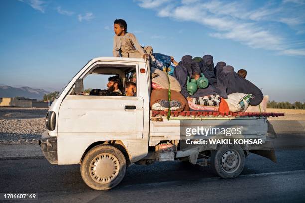 In this photograph taken on November 12 Afghan refugees with their belongings sit atop a truck as they head from a makeshift camp near the...