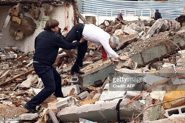 Chile's President Rafael Pinera stumbles and falls on the rubble during a visit to the demolition works of social housing in Bajos de Mena, Puente...