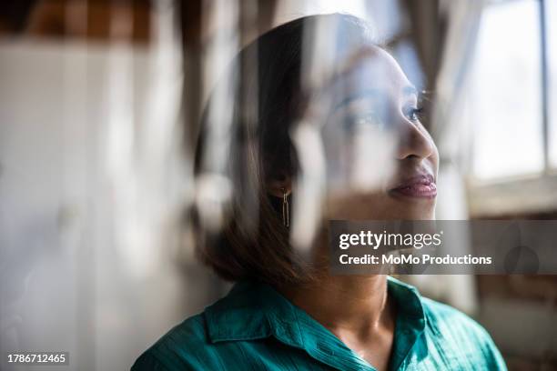 portrait of female businesswoman reflecting in glass window - reportage foto e immagini stock