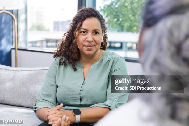 mature woman focuses on unrecognizable senior female friend - psychotherapy stock pictures, royalty-free photos & images