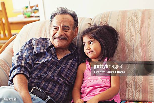 grandfather and granddaughter laughing on couch - ラテンアメリカ系民族 ストックフォトと画像