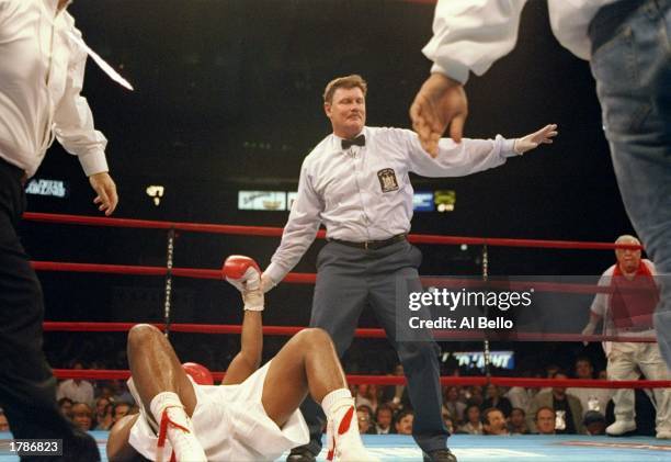 Riddick Bowe is on the canvas and has his arm raised to be declared the winner by referee Wayne Kelly. The fight was stopped with a low blow by...