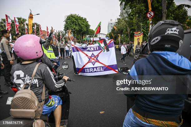People take part in a demonstration in Surabaya on November 17, 2023 in solidarity with the Palestinian people to call for boycotting what they...