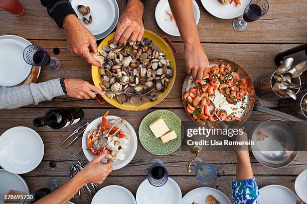 hands serving shellfish meal around wooden table - reaching across table stock pictures, royalty-free photos & images