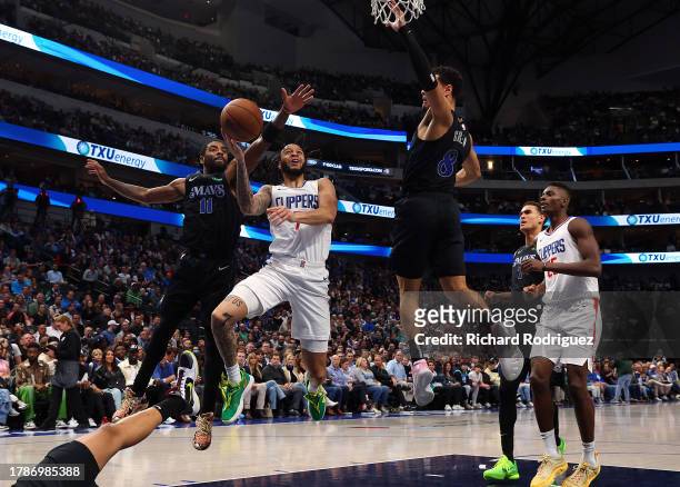 Amir Coffey of the LA Clippers goes up for a shot against Kyrie Irving of the Dallas Mavericks and Josh Green of the Dallas Mavericks in the fourth...