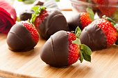 Dark chocolate covered strawberries lying on a cutting board