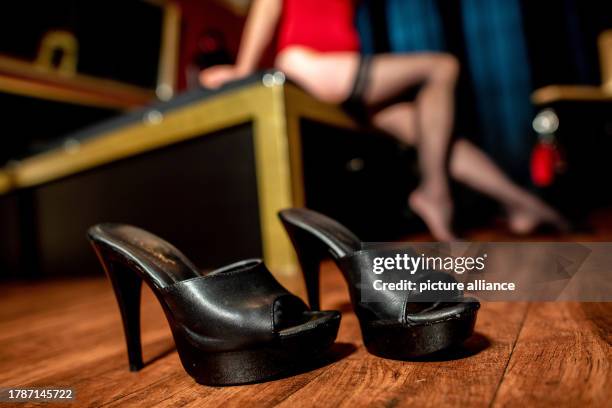November 2023, Lower Saxony, Oldenburg: Shoes stand in a brothel while a prostitute sits on a bed in the background. Photo: Hauke-Christian...