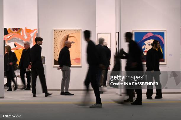 Visitors walk past artworks of Andy Warhol, 'With Hat ' and Alex Katz, 'Straw Hat 2' at the "Art Cologne" art fair in Cologne, western Germany on...
