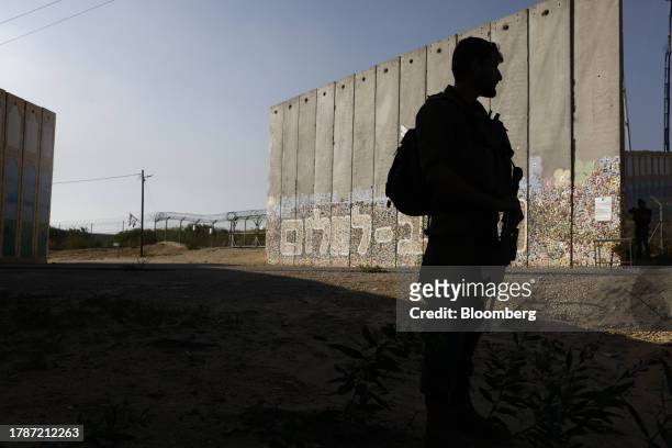 An Israeli soldier on patrol beside a protective security barrier decorated with "Path for Peace" near the border fence with Gaza Strip, left, in the...