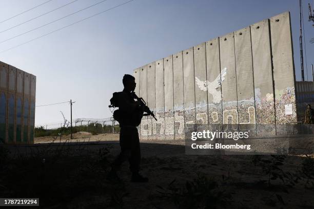 Israeli soldiers patrol beside a protective security barrier decorated with "Path for Peace" near the border fence with Gaza Strip, left, in the...