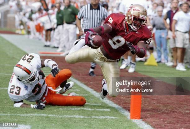 Flanker Peter Warrick of the Florida State Seminoles makes a touchdown as cornerback Duane Starks of the Miami Hurricanes misses the tackle during a...