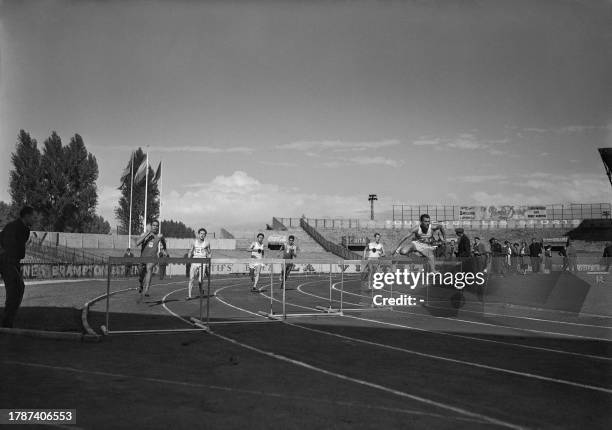 Competitors jump during the men's 400-meter hurdles, led by Romanian hurdler Ilie Savel , German Kurt Bonah and German Wolfgang Fischer on September...