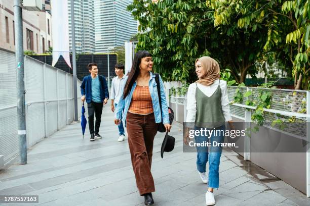 south east asian youth in the city, two young women with their partners walking and talking - malaysian culture stock pictures, royalty-free photos & images
