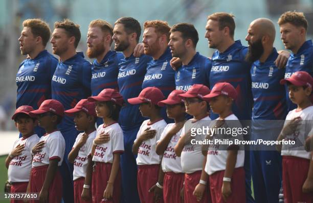 David Willey of England sings the national anthem with Jos Buttler and Ben Stokes before the ICC Men's Cricket World Cup India 2023 between England...