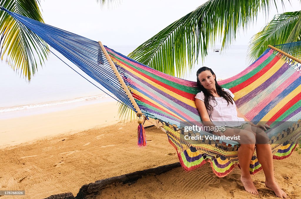 Girl sitting on hammock by the beach w/ palm trees