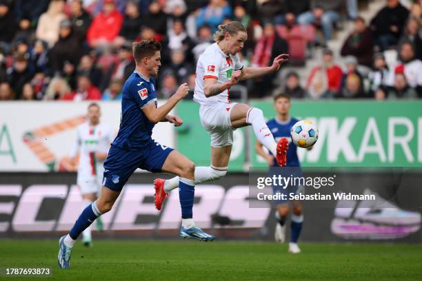 Fredrik Jensen of FC Augsburg kicks the ball ahead of Marius Buelter of TSG 1899 Hoffenheim during the Bundesliga match between FC Augsburg and TSG...