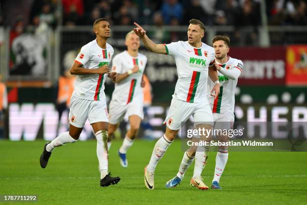 Ermedin Demirovic of FC Augsburg celebrates after scoring the team's first goal with teammates Felix Uduokhai and Elvis Rexhbecaj during the...