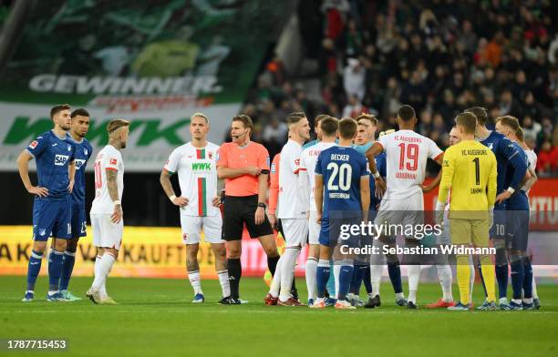 Players from both teams and referee Felix Brych meet in the middle of pitch as the game is interrupted during the Bundesliga match between FC...