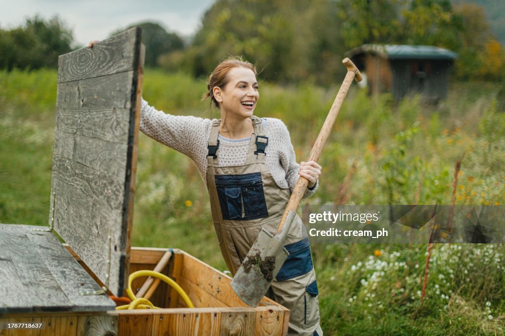 Junge Frau hält eine Schaufel und arbeitet auf einem landwirtschaftlichen Feld