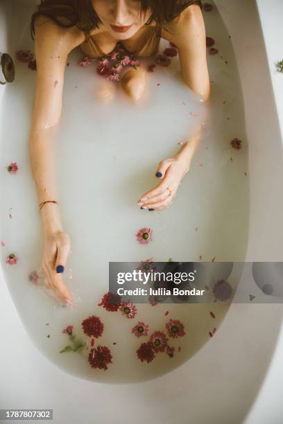 young beautiful woman taking flowering milky bath - milk pumping stock pictures, royalty-free photos & images