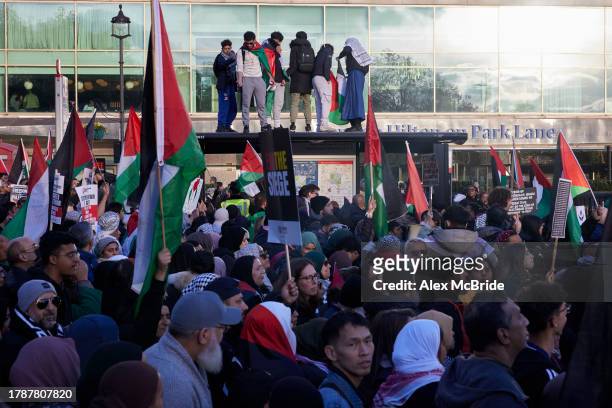 Protestors stand on top of a bus stop at a march for ceasefire in Gaza on November 11, 2023 in London, England. The protest's organisers, which...
