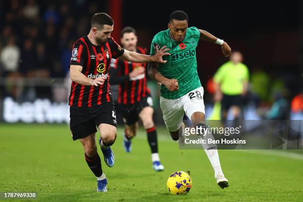 Joe Willock of Newcastle United runs with the ball whilst under pressure from Lewis Cook of AFC Bournemouth during the Premier League match between...