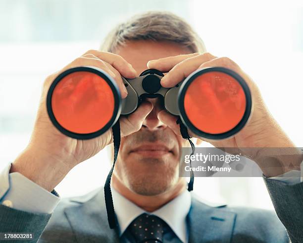 hombre de negocios mirando a través de binoculares - mirar a través fotografías e imágenes de stock