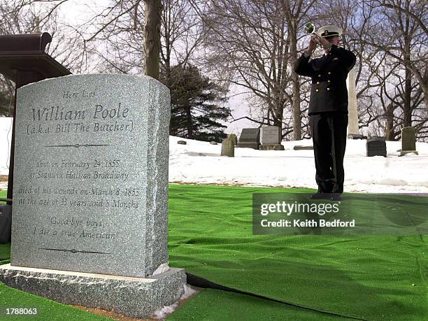 Merchant Marine Midshipman David Gilles plays "Taps" after unveiling the tombstone of William "Bill The Butcher" Poole during a ceremony at Greenwood...