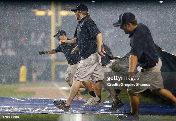 The grounds crew pulls the tarp onto the field during the eighth inning in a game between the Cleveland Indians and the Detroit Tigers at Comerica...