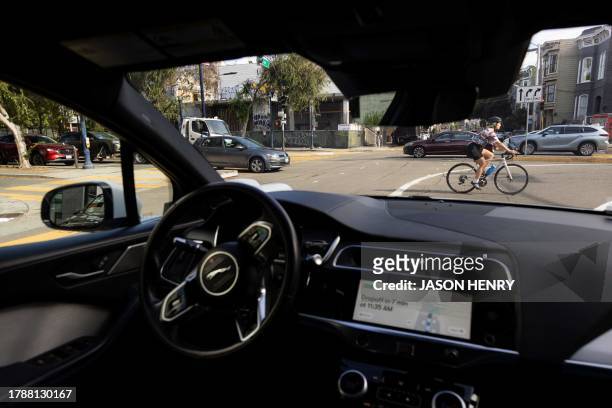 Cyclist passes in from of a Waymo autonomous vehicle on Oak Street in San Francisco, on November 17, 2023.