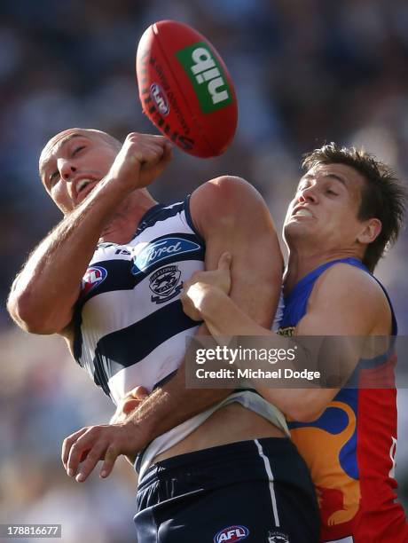 James Podsiadly of the Cats gets tackled by Jed Adcock of the Lions during the round 23 AFL match between the Geelong Cats and the Brisbane Lions at...