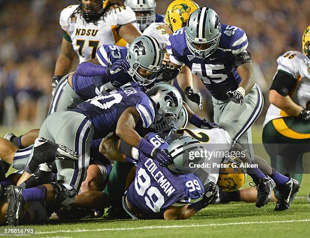 Defenders Valentino Coleman, Blake Slaughter and Marquel Bryant of the Kansas State Wildcats tackle running back John Crockett of the North Dakota...