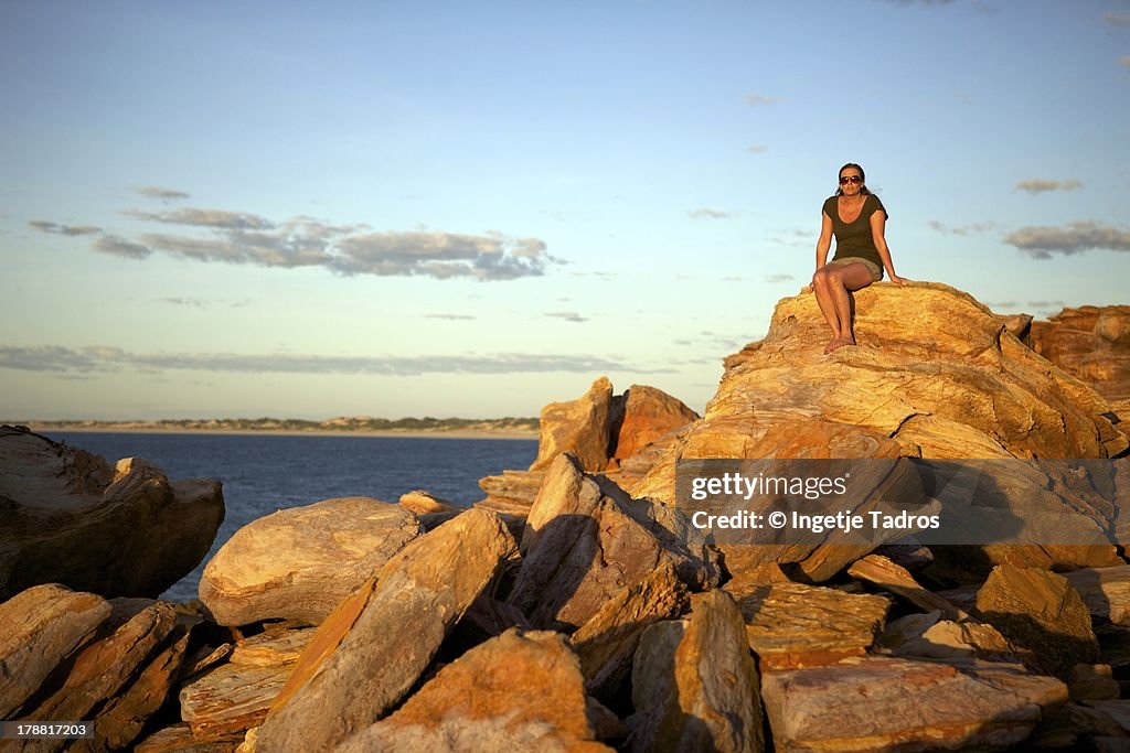 Woman sitting on red rocks