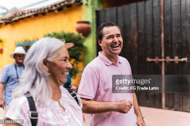 senior tourist friends talking while walking through tourist town - mexico stock pictures, royalty-free photos & images