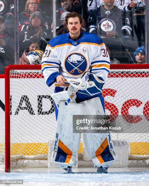 Goaltender Eric Comrie of the Buffalo Sabres looks on from the crease prior to puck drop against the Winnipeg Jets at the Canada Life Centre on...