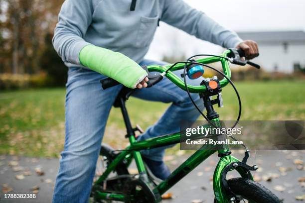 boy rides bike with cast on his broken arm - broken arm stock pictures, royalty-free photos & images