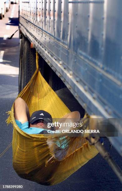 Truck driver sleeps in a hamock hoisted on his vehicle as demonstrators have blocked the roads in Guatemala City 02 April 2003. Un conductor duerme...