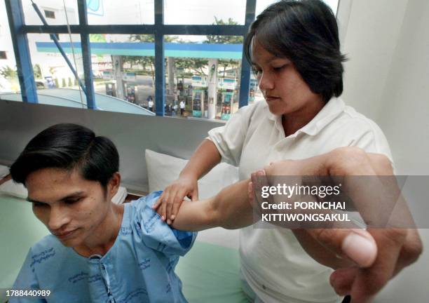 Woman massages a driver at gas station in Bangkok, 14 January 2003. The idea of massage in a gas station is to help motorists relax who are tired...