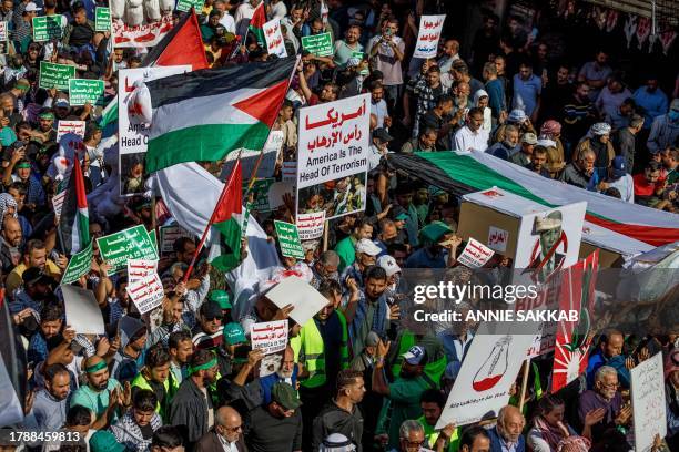 Amman, Jordan. Hundreds of demonstrators carry placards with the words 'America is the head of terrorism' and Palestinian flags during a solidarity...