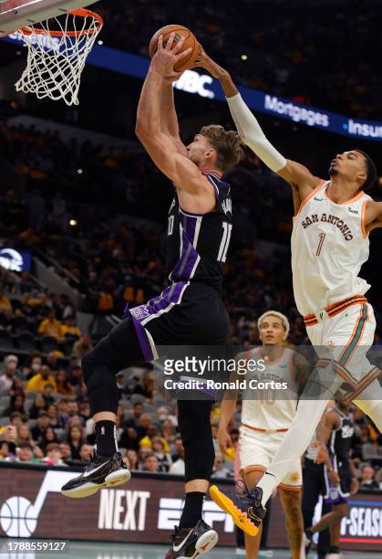 Domantas Sabonis of the Sacramento Kings scores despite the effort of Victor Wembanyama of the San Antonio Spurs in the second half of a NBA...