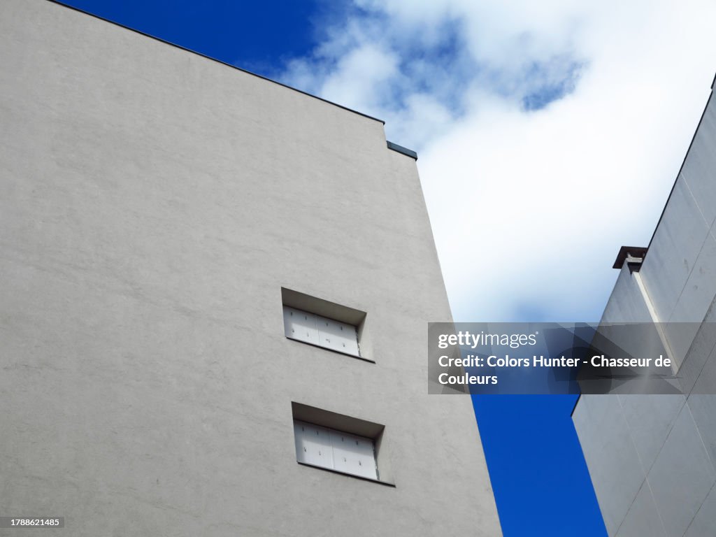 White walls with two windows with a blue and cloudy sky in Paris, France