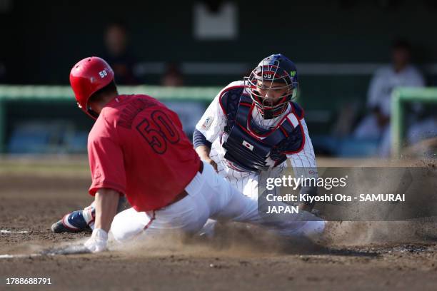 Kento Nakamura of the Hiroshima Carp is tagged out by Catcher Kota Ishibashi of Samurai Japan on the home plate in the 4th inning during a practice...