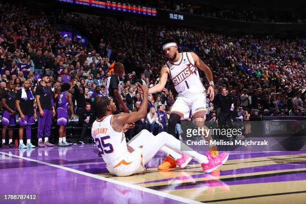 Devin Booker of the Phoenix Suns helps up Kevin Durant during the game against the Utah Jazz during the In-Season Tournament on November 17, 2023 at...