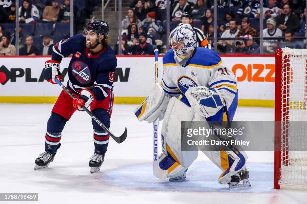 Alex Iafallo of the Winnipeg Jets and goaltender Eric Comrie of the Buffalo Sabres keep an eye on the play during second period action at the Canada...