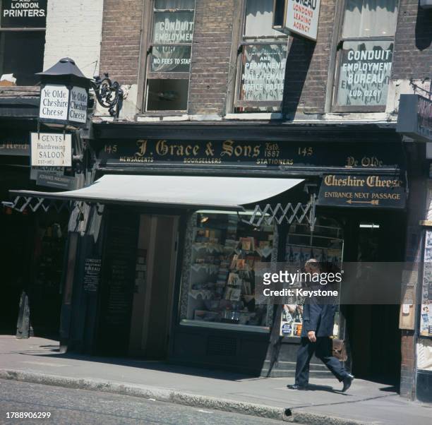 The shopfront of J Grace & Sons newsagents, booksellers and stationers, featuring signs pointing to the entrance of the Ye Olde Cheshire Cheese...