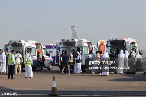 Volunteers and ambulances wait on the tarmac in Abu Dhabi on November 18 upon the arrival of the plane carrying evacuated Palestinians from Gaza as...