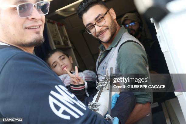 Volunteers transport a wounded Palestinian child off the plane upon their arrival in Abu Dhabi on November 18 after being evacuated from Gaza as part...