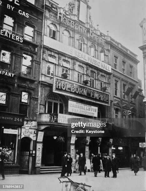 Pedestrians outside the Holborn Empire, a theatre and music hall, advertising appearances by 'Carroll Levis and his latest BBC Discoveries, 12 New...