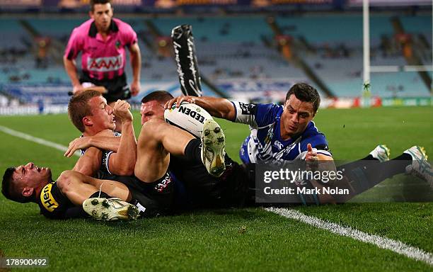 The Panthers defence foils a try by Trent Hodkinson and Sam Perrett of the Bulldogs during the round 25 NRL match between the Canterbury Bulldogs and...