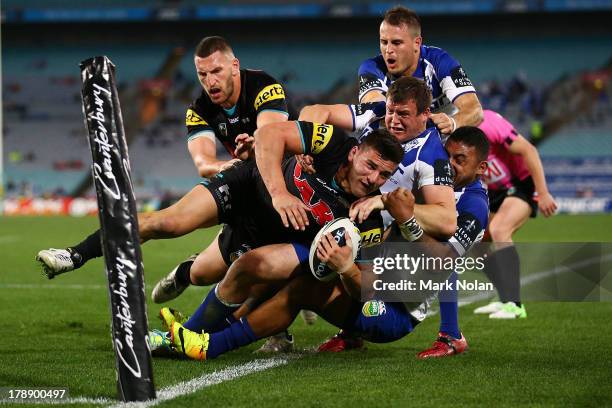 Josh Mansour of the Panthers is bundled into touch by the Bulldogs defence during the round 25 NRL match between the Canterbury Bulldogs and the...